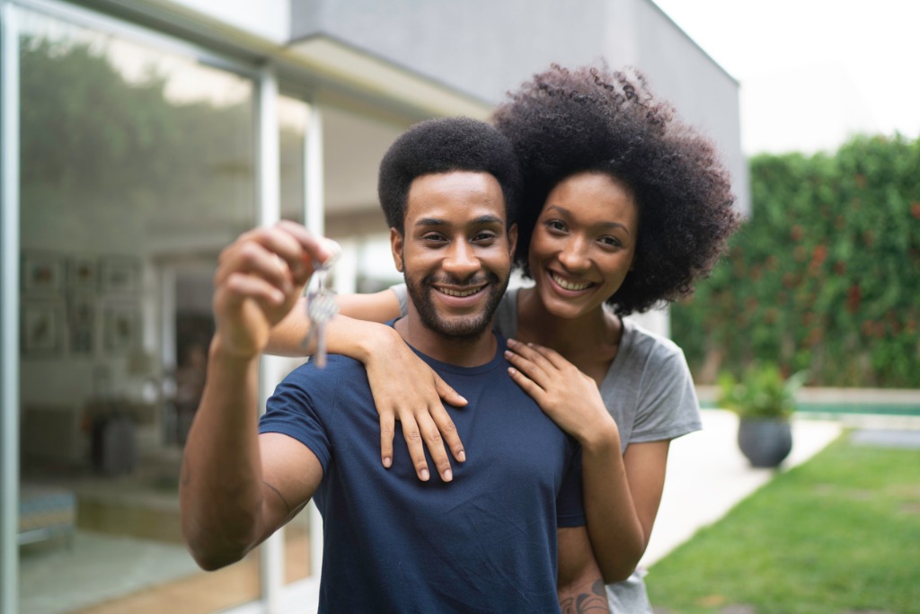 Young couple holding up a key to their new house